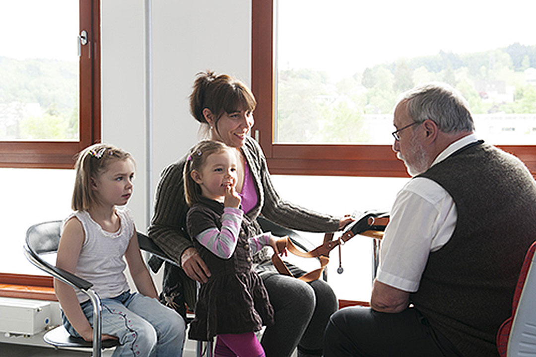 Ein Arzt berät zwei Kinder und ihre Mutter