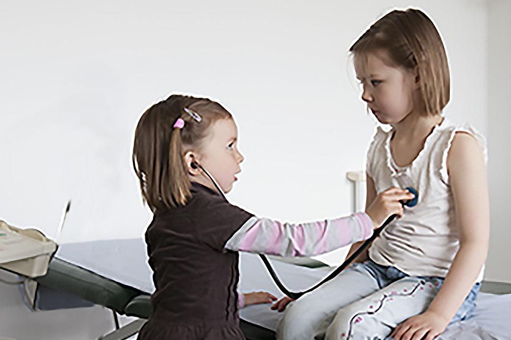 Ein kleines Mädchen spielt mit einem Stethoskop und untersucht ein anderes Mädchen